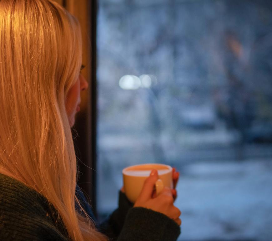 woman holding mug and looking out window