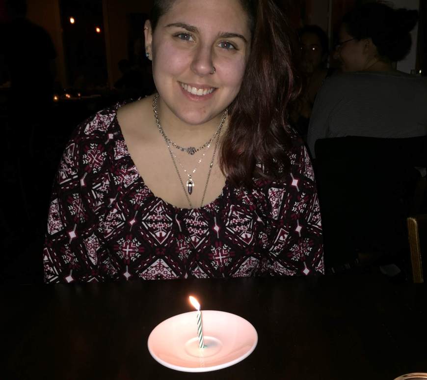 renata smiling in front of a plate with a lit candle
