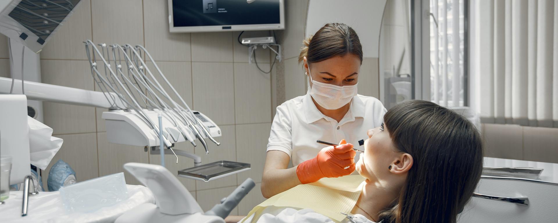 woman in dentists chair with dentist using dental apparatus in her mouth