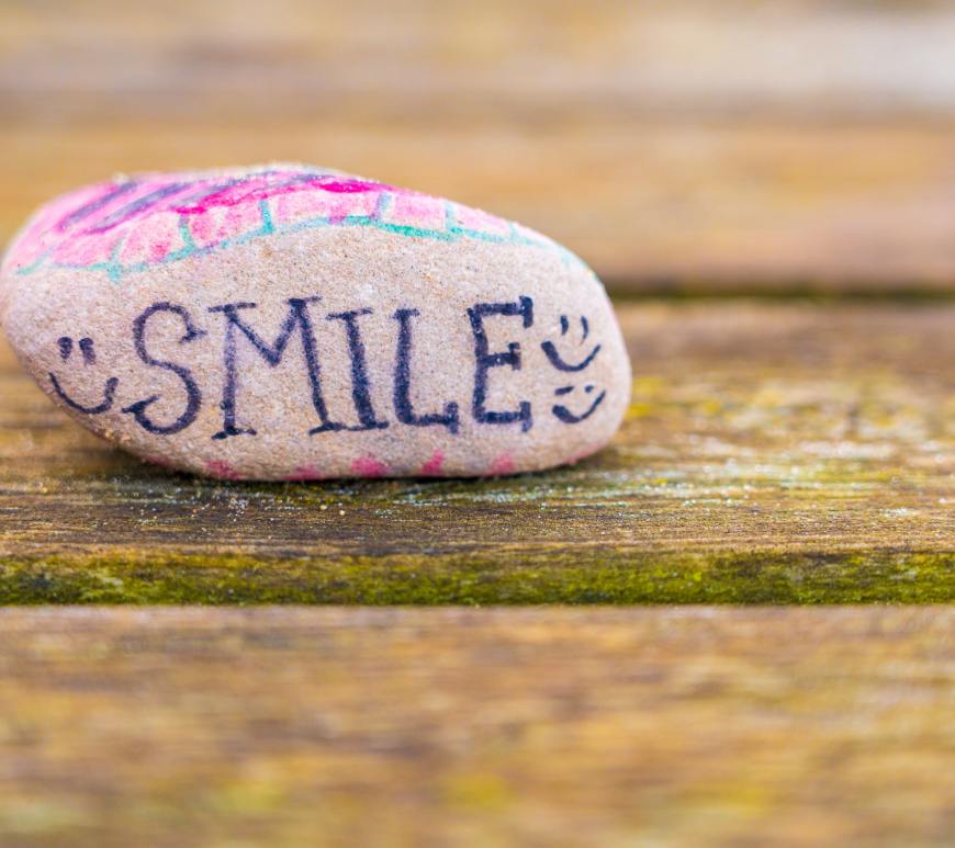 rock with colors, smiley faces, and the word "SMILE" painted on