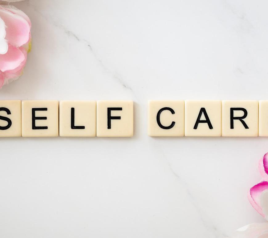 tiles that read "self care" on a white marbled background with flowers
