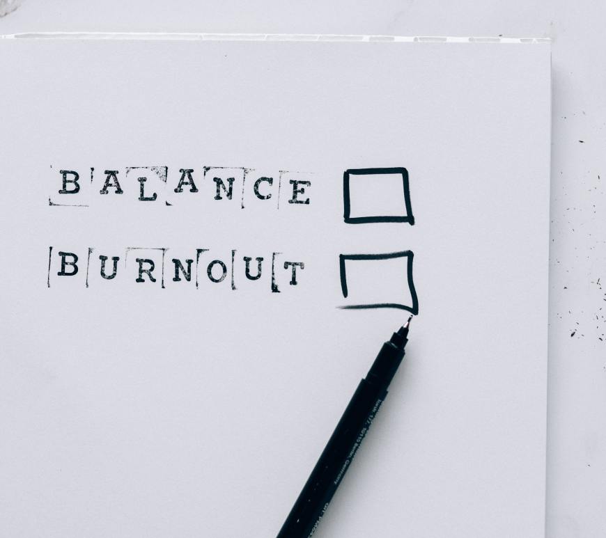 paper that says "balance" and "burnout" with checkboxes and a pen