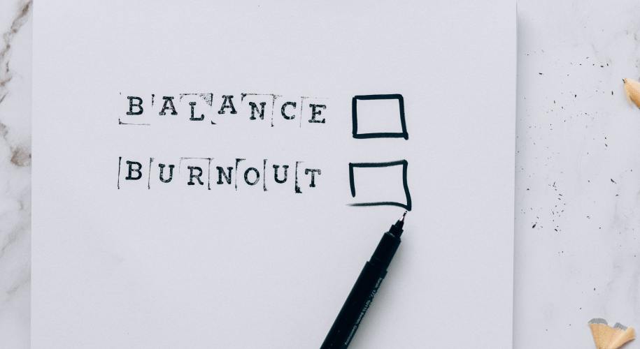 paper that says "balance" and "burnout" with checkboxes and a pen