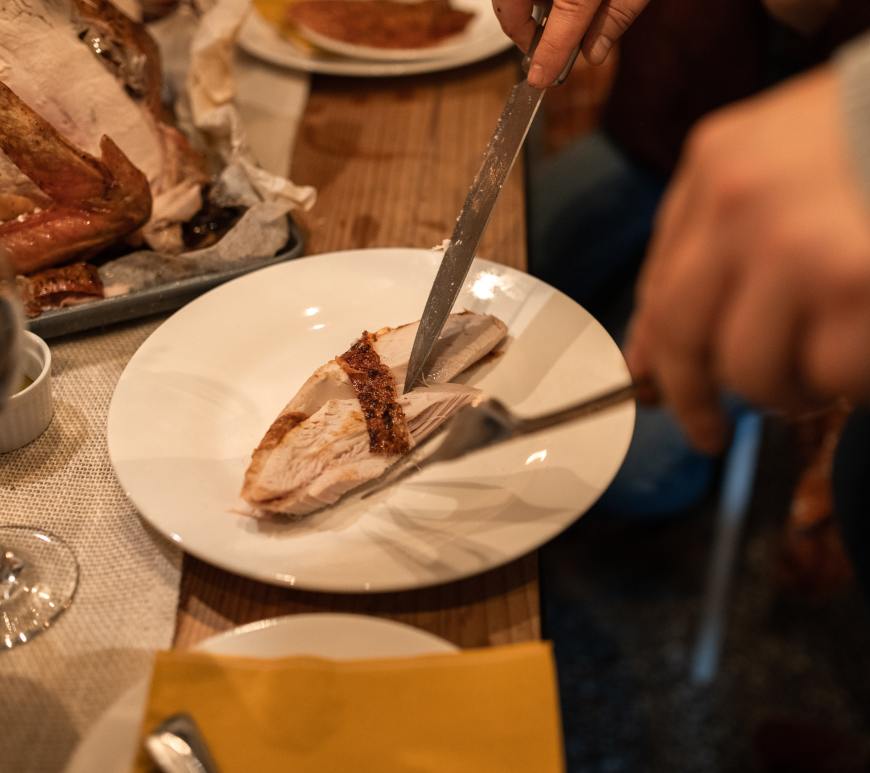 person cutting piece of white meat turkey