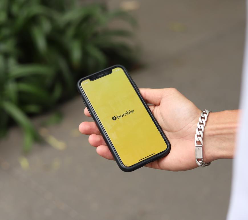 hand holding smartphone with bumble logo on screen