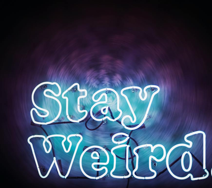 neon sign that says "stay weird." on a dark background